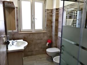 ein Bad mit einem WC, einem Waschbecken und einem Fenster in der Unterkunft ALEXA casa vacanze in Pero