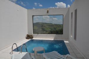 uma piscina com cadeiras e uma grande janela em Pousada Villa dos Leais em Serra Negra
