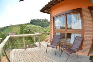 two chairs and a table on a wooden deck at Pousada Villa dos Leais in Serra Negra