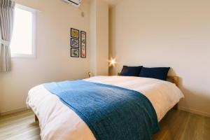 a bedroom with a large bed with a blue blanket at TEN APARTMENT HOTEL in Fukuoka