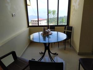 einen Tisch und Stühle in einem Zimmer mit Fenster in der Unterkunft Megafarm Inn in Mahabaleshwar
