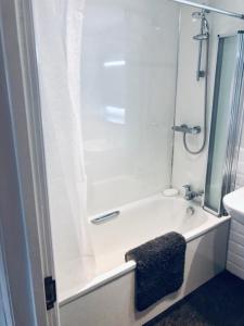 a white bathroom with a shower and a bath tub at The Juniperlea Inn in Pathhead