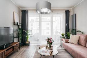 - un salon avec un canapé rose et une grande fenêtre dans l'établissement Garden Apartments by LoftAffair, à Cracovie