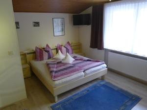 a bedroom with a bed with purple pillows and a window at Alpenappartement Claudia in Piesendorf