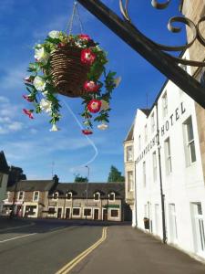 a basket of flowers hanging from a building on a street at Dreadnought Hotel in Callander