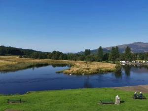 a river with two benches in a grassy field at The Caledonian Thistle Hotel in Callander