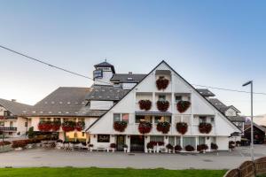 ein großes weißes Gebäude mit Blumentopfen an der Fassade in der Unterkunft Jagodic Garni Hotel in Cerklje na Gorenjskem