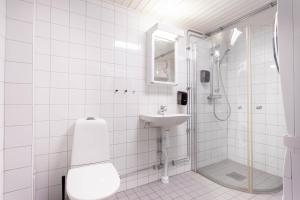 a white tiled bathroom with a shower and a sink at ApartDirect Gamla Stan II in Stockholm