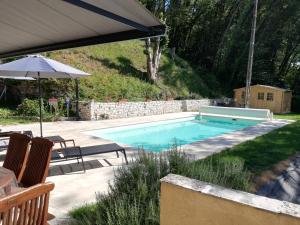 a swimming pool with two chairs and an umbrella at Villa les Bisets 497 rue de fenelon in Carlux