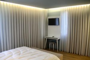 a bedroom with a bed and a desk and a television at A Rendilheira Charm Suites in Vila do Conde