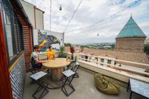 un groupe de personnes assises autour d'une table sur un balcon dans l'établissement Envoy Hostel and Tours, à Tbilissi