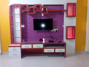 um centro de entretenimento com uma televisão numa parede roxa em Megafarm Inn em Mahabaleshwar