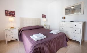 a bedroom with a purple bed with two towels on it at Casa María in Nerja