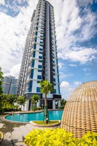 a tall building with a swimming pool in front of it at Stay @ Almas Puteri Harbour in Nusajaya