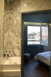 baño con lavabo, cama y ventana en A Rendilheira Boutique Hotel, en Vila do Conde