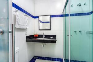 a bathroom with a sink and a glass shower at Hotel Beach Hills in Porto Seguro