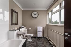 a bathroom with a sink toilet and a clock on the wall at Hartsfield Manor in Dorking +33 photos