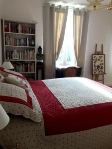 a bedroom with a bed with a red and white blanket at L'atelier de Jocelyne in Beuzeville