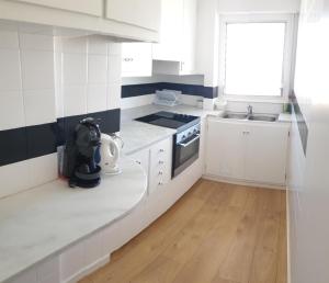 a white kitchen with white cabinets and a window at Marquina in Cadaqués