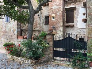 una cerca frente a un edificio de ladrillo con un árbol en Torre alle Antiche Mura en Montepulciano
