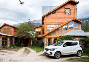 un camion blanc garé devant une maison en bois dans l'établissement Jardín de Rosas Hostel, à El Bolsón