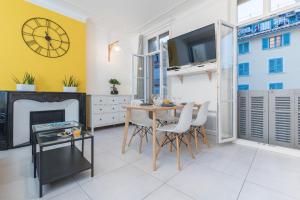 a living room with a table and a clock on the wall at L'Olivaroise in Toulon