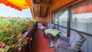 einen Balkon mit einem Tisch, Stühlen und Blumen in der Unterkunft Hotel Alpina in Hagnau