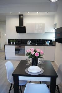 a table with a vase of flowers on it in a kitchen at Black & White Apartament in Toruń