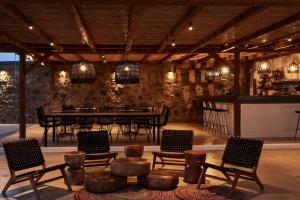 a dining room with chairs and a table and a bar at Almyra Guest Houses in Paraga