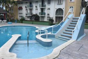 a swimming pool with a slide in front of a building at RAIROYALE AT SAND CASTLES in Ocho Rios