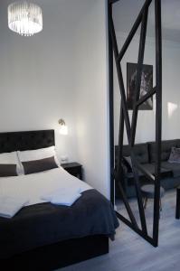 a bedroom with a black and white bed and a chair at Black & White Apartament in Toruń