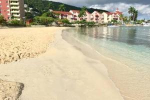a sandy beach with houses in the background and the ocean at RAIROYALE AT SAND CASTLES in Ocho Rios