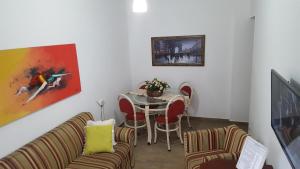 een woonkamer met een tafel en stoelen en een schilderij bij Santos Apartamento Frente Mar - Ar Condicionado na Suíte - Garagem Privativa -Internet - TV a Cabo in Santos