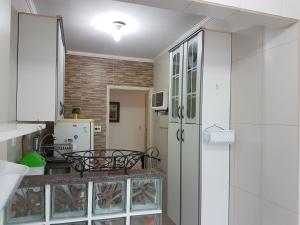 een keuken met witte kasten en een koelkast bij Santos Apartamento Frente Mar - Ar Condicionado na Suíte - Garagem Privativa -Internet - TV a Cabo in Santos