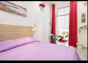 um quarto com uma cama roxa e uma mesa em Flower Power em Nápoles