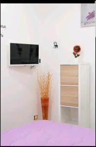 um quarto com uma televisão numa parede branca em Flower Power em Nápoles