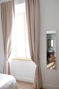 a bedroom with a window with curtains and a mirror at L'Alighieri in Monterotondo