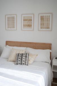 uma cama com lençóis brancos e duas fotografias na parede em L'Alighieri em Monterotondo
