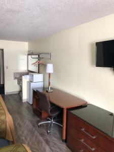 a room with a desk with a computer and a tv at Western Inn South in Kearney