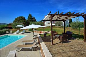 a pool with chairs and umbrellas next to a pool at Azienda Agricola Fornacelle in San Gimignano