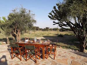 a wooden table with chairs around it in a field at Maji Moto Maasai Cultural Camp in Narok