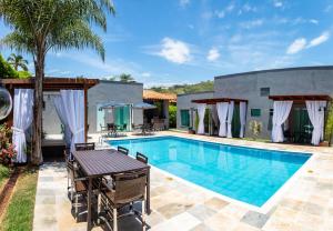 a pool with a table and chairs next to a house at Escarpas Eco Village in Capitólio