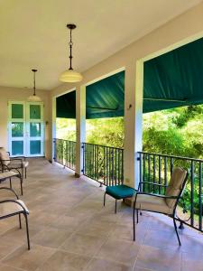 a screened in porch with chairs and windows at Tio Pepe’s Guest House in Aibonito