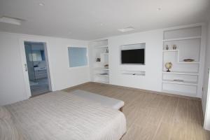 a white bedroom with a bed and a flat screen tv at Orly Club Coral Arena Dorada in Puerto del Carmen