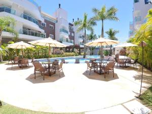 un patio con mesas y sombrillas junto a una piscina en Boulevard Bombinhas, en Bombinhas