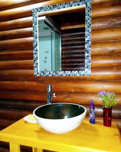 baño con lavabo y espejo en una pared de madera en Cabaña Alamos Altos en Belén de Escobar