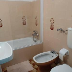 a bathroom with a toilet and a tub and a sink at Home Village in Vila do Bispo