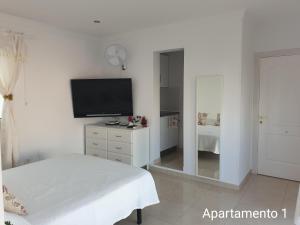 ein weißes Schlafzimmer mit Bett und Flachbildfernseher in der Unterkunft Apartamento Kings Vegueta in Las Palmas de Gran Canaria