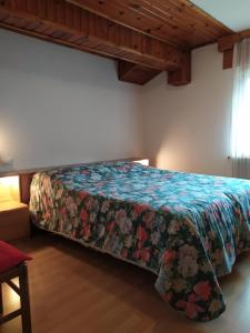 a bedroom with a bed with a colorful bedspread at Mansarda Accogliente Falcade Dolomiti in Falcade