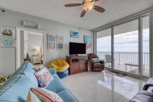 a living room with a blue couch and a flat screen tv at The Beach Club Resort and Spa in Gulf Shores